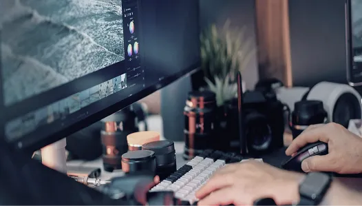 モニターに表示された波の映像を見ながら、カラーグレーディング調整を行う動画編集者の手元とデスク